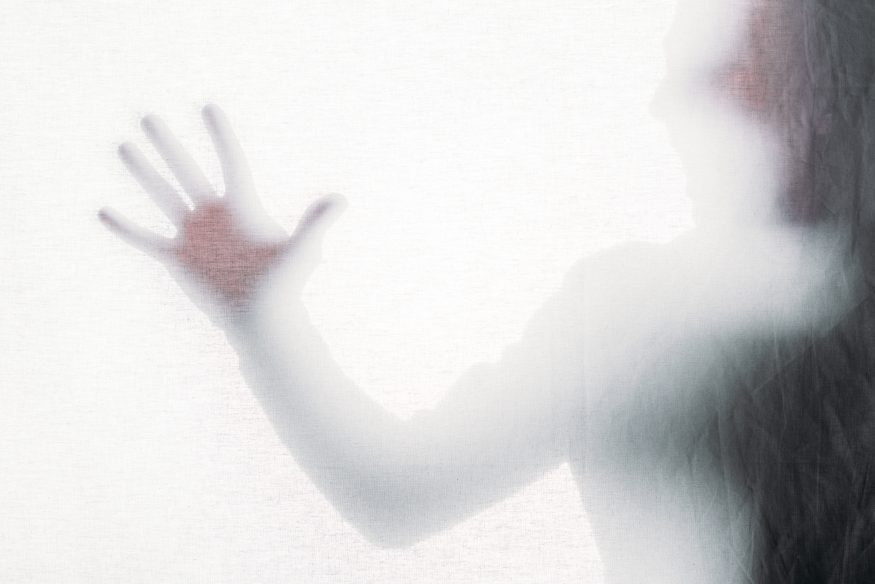 Blurry silhouette of a person touching frosted glass